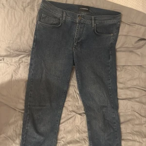 Blå jeans från J.Lindeberg - Snygga blå jeans från J.Lindeberg med klassisk femficksdesign och diskret logga på myntfickan. Jeansen har en rak passform och är tillverkade i slitstarkt bomullsjeans. Perfekta för dig som gillar stilrena och tidlösa plagg. 32/32 ord 1699