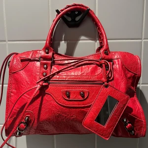 City bag - Ruby - (OBS! inte begagnad! Finns även att beställa via vår hemsida www.ivysthlm.se) CITY BAG – Den perfekta statment väskan som livar upp varje vardags-outfit. Lika praktisk som snygg och fungerar både till skola & fest – Ja, din dator får plats! (väskan levereras med ett långt, justerbart axelband för extra bekvämlighet) Storlek: 38×10×23 cm. Äkta läder