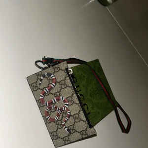 Gucci korthållare runt halsen - Gucci lanyard snake korthållare, i färgen beige. Helt ny och jätte fin. Svåra att få tag på dem säljs ej längre.