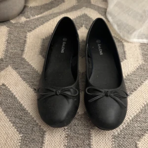 Svarta ballerinaskor med rosett - Svarta ballerinaskor från Åhléns, använda ett fåtal gånger 