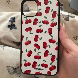 Körsbär skal iPhone 11 - Söt vit med körsbär skal frän bjornberry. Använde men finns inga skador, precis som ett helt nytt skal. Till iPhone 11