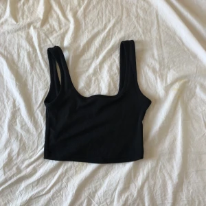 Svart ribbad croppad linnetopp - En svart croppad linnetopp fyrkantig urringning. Toppen är ribbad och har mkt stretch i.