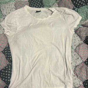 Vit t-shirt från Gina Tricot - En basic vit t-shirt från Gina Tricot i storlek M. T-shirten har rund halsringning och korta ärmar, perfekt för en clean och enkel look. Tillverkad i mjuk bomull som känns skön mot huden. Passar till allt och är ett måste i garderoben.