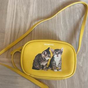 Axelremsväska - En liten färg glad väska som är i bra skick. Otroligt gullig. (OBS den kan verka större i fotot, den är väldigt liten.)