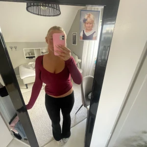 Vinröd långärmad topp med djup ringning - Säljer en vinröd långärmad topp med djup, rundad ringning. Modellen är tight och croppad, perfekt att styla med höga jeans eller kjol. Materialet känns mjukt och stretchigt, vilket gör den riktigt bekväm att bära.