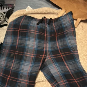 Rutiga mjukisbyxor från W.A.S. - Snygga mjukisbyxor från W.A.S. i rutig design med blå, svart och röda toner. Byxorna har resår och snörning i midjan för skön passform. Perfekta för chill dagar eller när du vill vara bekväm men ändå se cool ut.