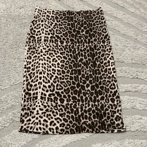 Leopardmönstrad långkjol - Snygg långkjol med leopardmönster i svart och beige. Kjolen har en rak passform och är perfekt för dig som vill sticka ut med en trendig look. Mjuk och skön att bära, passar till många olika stilar.