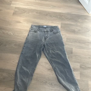 Grå tvättade jeans från grunt - Säljer ett par grå jeans från Gina Tricot med tvättad look. Klassisk femficksmodell, raka ben och normal passform. Jeansen har knapp och dragkedja framtill samt bälteshällor. Perfekta för en avslappnad stil.