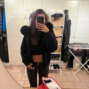 Svart stickad jacka med pälshuva - Mysig svart stickad jacka med fluffig pälskant på huvan. Modellen är croppad med breda ribbade muddar och dragkedja framtill. Perfekt för dig som vill ha en trendig och varm look. Ord pris; 1800kr😊 Bara skriva om ni vill ha fler bilder