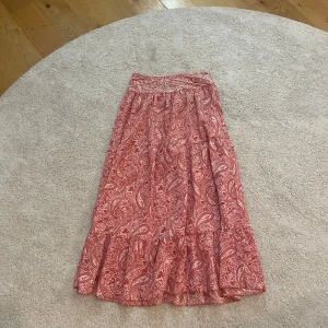 Viral långkjol - Supersnygg långkjol från Zara i rött och vitt paisleymönster. Kjolen har pärldetaljer upptill och är gjord i ett lätt och luftigt material, perfekt för varma dagar. Resår i midjan. Kjolen är dessvärre för kort för mig och jag kommer därför inte att skicka bilder när jag har den på mig💓💓