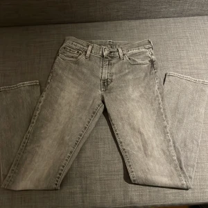 Levis 511 grå jeans W30 L32 - Snygga Levis 511 jeans i grå tvätt med klassisk femficksdesign och svarta detaljer på bakfickan. Jeansen har en slim passform och är tillverkade i mjukt denim. Perfekta för dig som gillar en stilren och modern look.