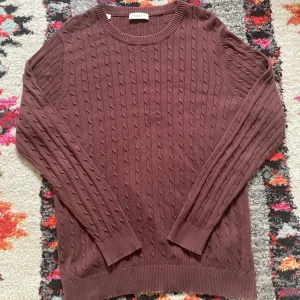 Brun kabelstickad tröja Selected Homme - Säljer en brun kabelstickad tröja från Selected Homme i storlek S. Tröjan har rund halsringning, ribbade muddar och är långärmad. Perfekt för dig som gillar klassisk stil. Materialet är mjukt och skönt, passar bra till jeans eller chinos.