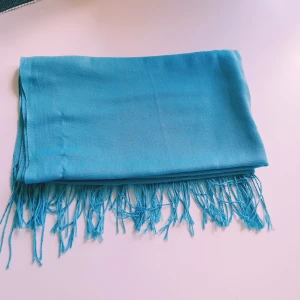 Turkos sjal med fransar - En stilren turkos halsduk med tunna fransar i ändarna. Sval och lätt, perfekt att slänga över axlarna för en färgklick. Tunt tyg som ger ett luftigt intryck och passar bra till många outfits.  Helt skick dock noppror