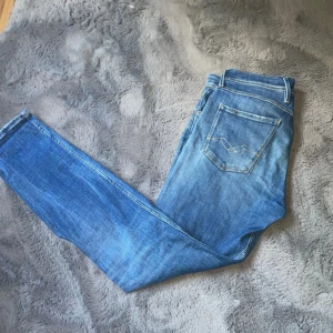 Blå Replay jeans med hög kvalité  - Snygga blå jeans från Replay med klassisk femficksdesign och smal passform. Jeansen har ljusa slitningar och tydliga kontrastsömmar. Tillverkade i mjukt denimtyg som sitter skönt hela dagen.
