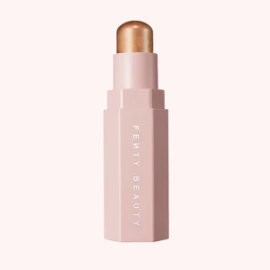 Fenty Beauty highlighter stick guld - Highlighter stick från Fenty Beauty i en snygg guldig nyans. Kommer i en sexkantig, ljusrosa hylsa med vit text. Perfekt för att ge glow till kindben, näsrygg och amorbåge. Enkel att applicera tack vare den krämiga formulan.