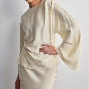 By Malina - Satin blus cremefärgad  från By Malina. Vida långa ärmar, rund halsringning. Lite sönder vid nacken men verkligen inget man tänker på när man bär den och kan åtgärdas enkelt. 💛 Strl XS men passar även S