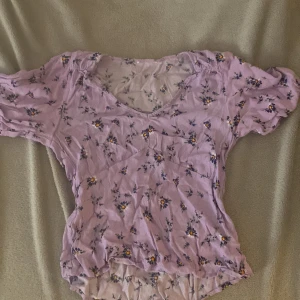 Blus  - En blommig blus som är lila