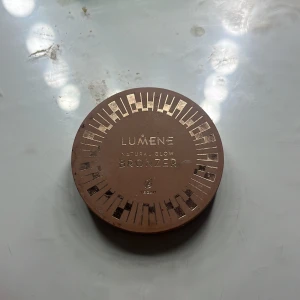 Lumene Natural Glow Bronzer - Lumene Natural Glow Bronzer i nyansen Arctic Summer. Kommer i en rund, brun plastförpackning med guldiga detaljer. Pudret har en varm, naturlig brun ton och är vegansk. Perfekt för att skapa en solkysst look och ge ansiktet extra dimension.