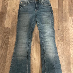 Blå bootcut jeans med utsvängda ben - Snygga blå jeans med bootcut och utsvängda ben. Klassisk femficksmodell och normalhög midja. Jeansen har en lätt tvättad look och är perfekta för dig som gillar retrovibbar. Tillverkade i mjukt denimtyg för skön passform. Använda men bra skick😊