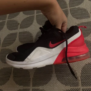 Nike Air Max sneakers svart/röd - Nike Air Max sneakers i svart mesh med röda och vita detaljer. Skorna har synlig Air-dämpning i hälen, svart snörning och en vit/röd sula. Perfekta för dig som gillar sportig och modern stil.