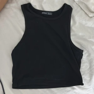 Svart croppad linnetopp från SHEIN - En stilren svart croppad linnetopp från SHEIN i storlek XS. Toppen har breda axelband och rund halsringning, perfekt för en clean och enkel look. Materialet är mjukt och stretchigt, vilket gör den superbekväm att bära till jeans eller kjol.