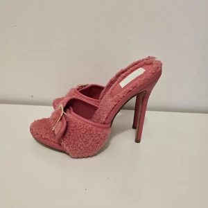 Rosa fluffiga klackar med spänne - Unika rosa klackar med hög klack och fluffigt teddy-material över hela skon. Snyggt guldfärgat spänne framtill och öppen tå. Perfekta för dig som vill sticka ut med en cool och trendig look.
