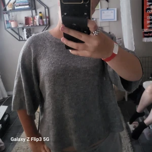 Grå stickad tröja med vida ärmar - Mysig grå stickad tröja med rund hals och vida, lite kortare ärmar. Perfekt för lager på lager och chill dagar. Enkel och stilren design som funkar till det mesta. Skön och mjuk känsla tack vare det stickade materialet.