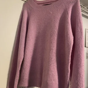 Ljusrosa stickad tröja Vero Moda - Supermysig ljusrosa stickad tröja från Vero Moda. Tröjan har rund halsringning, långa ärmar och ribbade muddar vid ärmslut och nederkant. Perfekt för lager-på-lager och chill dagar. 