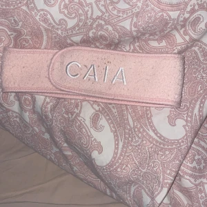 Rosa diadem från CAIA - Säljer ett ljusrosa diadem från CAIA med broderad logga framtill. Diademet är gjort i mjuk frotté och har kardborreknäppning för enkel justering. Perfekt när du vill hålla håret borta vid sminkning eller hudvård.