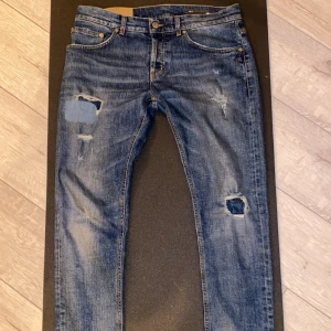 Blåa slim fit jeans från dondup - Snygga blå jeans från dondup i slim fit-modell med slitningar och lagade hål på benen. Klassisk femficksdesign, orange sömmar och cool detalj med broderad logga bak. Perfekta för dig som gillar en avslappnad och trendig look. Passformen för jeansen är mellan skinny/slim fit. Klär man sig som en grishare så klär de dig perfekt! Hör av dig vid funderingar😆