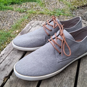 Grå sneakers från Iguassu Trade - Snygga grå sneakers från Iguassu Trade med bruna snören och vit sula. I skorlek 44. Inte mycket anvönda! Skorna har en stilren design med rund tå och är tillverkade i textilmaterial som ger en avslappnad vibe. Perfekta för dig som gillar en clean och enkel look.