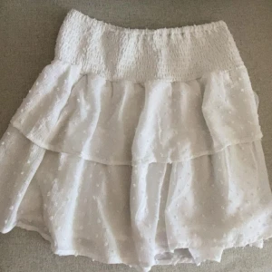 Vit volangkjol från Ginatricot - Supersöt vit kortkjol med volanger från Ginatricot. Midjan är stretchig och resten av kjolen har prickiga detaljer. Kjolen är i storlek 158/164. Skriv för frågor eller fler bilder!💕💕