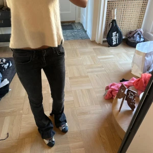 Svarta bootcut jeans låg midja - Säljer ett par svarta jeans med bootcut och låg midja. Jeansen har klassisk femficksdesign och är i stretchigt material som sitter snyggt över höfterna och låren. Perfekta för dig som gillar en lite retro vibe och vill ha ett par jeans som sticker ut.