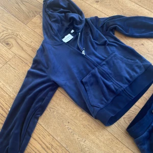 Marinblå velour hoodie Juicy Couture - Säljer en marinblå hoodie från Juicy Couture i mjuk velour med dragkedja, huva och broderad JC-logga på bröstet. Tröjan har långa ärmar och en stor ficka framtill. Perfekt för dig som gillar klassisk Y2K-stil och vill ha något riktigt comfy. Jag säljer också  ett par byxor men som är i storleken 8/9. Kan säljas enskilt men helst tillsammans. 250 för en och 400 för båda❤️