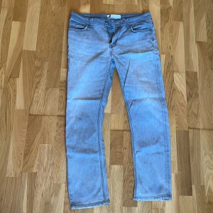 Ljusgråa jeans från Dressmann 34/30 - Säljer ett par ljusgråa jeans från Dressmann i klassisk rak modell. Jeansen har fem fickor, bälteshällor och stängs med dragkedja och knapp. Materialet är mjuk bomull med lite stretch för extra komfort. Perfekta för en avslappnad stil.