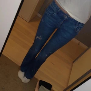Flared jeans  - Säljer ett par snygga jeans med lätt utsvängda ben (bootcut-still) midjemått cirka 69, passar dig som brukar ha w27-28 eller Eu 36-38, sitter bra, slitna framtill men det är en del av designen, bekväma och stretchiga (säljer för 120 men pris kan diskuteras)