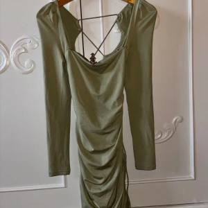 Långärmad klänning  -  Grön tight långärmad klänning med justerbar snörning i ryggen. Sitter skönt men är lite i tightaste laget för mig. Sitter i bra längd på mig som är 163cm. Har dubbel vaddering över bysten så behövs ingen bh.
