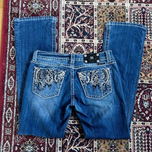 Miss Me Jeans - Jättesnygga bootcutjeans från Miss me med coola detaljer på bakfickorna och diamantdetaljer.🥰 Midjemått: 42,5cm rakt över Innerbenslängd: 83cm