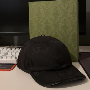Gucci keps - Snygg svart äkta keps från Gucci med diskret GG-logga över hela kepsen. Kepsen är utöver fräsch och inte mycket andvänd. Storlek L box kvitto följs med 