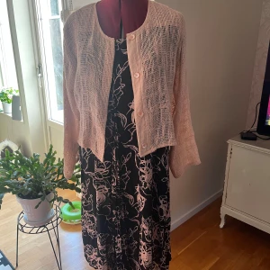 Svart blommig långklänning och kofta Masai S - Supersnygg svart långklänning från Masai med ljusa blommiga mönster. Klänningen har rund halsringning och korta ärmar. Tillverkad i en skön mix av bomull och viskos, perfekt för dig som gillar en avslappnad men ändå stilren look.