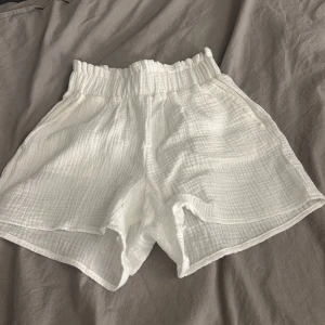 Vita högmidjade linneshorts - Superfräscha vita shorts i mjuk, krinklad bomull med hög midja och elastisk resår. Luftiga och perfekta för varma dagar, med en avslappnad passform som ger en chill vibe. Snygga att matcha med en crop top eller oversized t-shirt.❤️