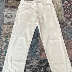 Vita straight leg jeans från H&M - Snygga vita jeans från H&M med loose fit och raka ben. Byxorna har justerbar midja och klassisk fyrficksdesign. Perfekta för en clean och fräsch look, lätta att matcha med allt. Materialet är bomull för en skön känsla hela dagen.