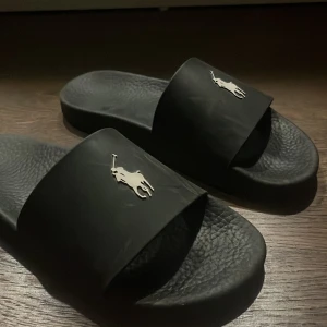 Svarta Ralph lauren tofflor  - Säljer dessa svarta Ralph lauren tofflor i ett bra skick|| storlek 42|| skick 9/10|| pris 349(diskuterbart)|| skriv vid minsta lilla fundering!