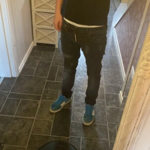 Svarta jeans från Dsquared2 - Säljer ett par svarta skinny jeans från Dsquared2 i storlek 44 mostsvarar typ 29 30. Jeansen har en mörk tvätt med diskreta slitningar och klassisk femficksdesign. Snygg Dsquared2-logga på bakfickan och dragkedja framtill. Perfekta för dig som gillar en smal passform och streetstil.