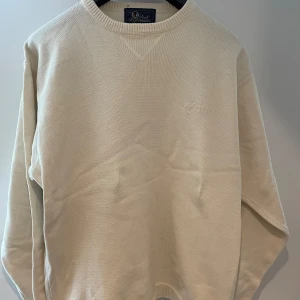 Beige stickad tröja Peak Performance XL - Snygg beige stickad tröja från Peak Performance i storlek XL. Tröjan har rund halsringning, diskret broderad logga på bröstet och ribbade muddar. Perfekt för dig som gillar en clean och stilren look.