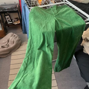 Gröna manchesterbyxor med raka ben - Snygga gröna manchesterbyxor med raka ben och klassisk passform. Byxorna har hög midja, sidfickor och stängs med knapp och dragkedja. Perfekta för dig som vill sticka ut med färg och gillar retrovibbar.