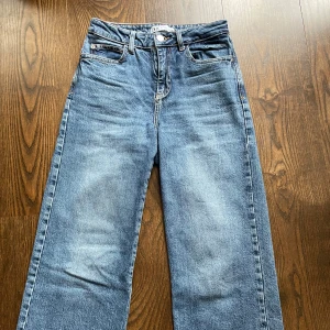 Blå raka jeans från Zara, stl 34 - Snygga blå jeans från Zara i rak modell med klassisk femficksdesign. Jeansen har hög midja och är tillverkade i bomull. Perfekta till sneakers eller boots för en chill look.