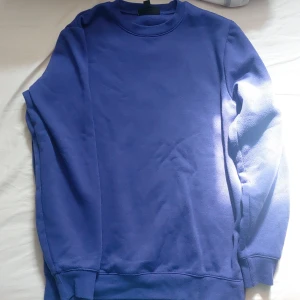 Lila sweatshirt med rund hals - En stilren blå sweatshirt med rund hals och långa ärmar. Tröjan har en klassisk passform och ribbade muddar vid ärmslut och nederkant. 