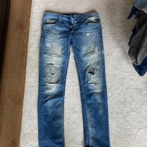 Replay blå slitna jeans, midja 30/32 - Blå jeans från Replay med slitna detaljer och trasiga partier framtill. Modellen har normal passform och klassisk femficksdesign. Jeansen har en snygg tvättad look och är tillverkade i bomull. Perfekta för en avslappnad streetstil.