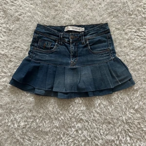 Mörkblå jeanskjol med volang - Lågmidjad jeanskjol omsydd från ett par jeans. Midjemått tvärsöver - ca 36cm Längd - 35cm